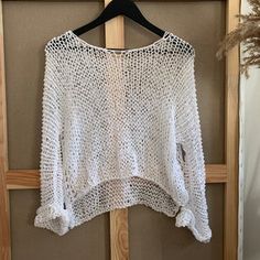 a white sweater hanging on a wooden hanger