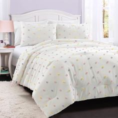 a white bed with polka dot comforter and pillows