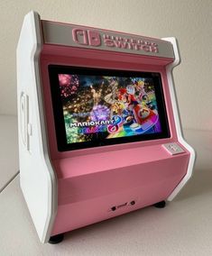 a pink and white arcade machine sitting on top of a table