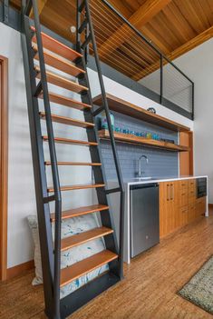 a kitchen area with a sink, stove and wooden stairs leading up to the upper floor