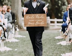 a man walking down the aisle holding a sign that says uncle tucker here comes your bride