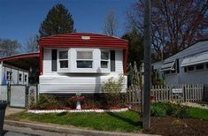 a white and red mobile home sitting on the side of a road next to a fence