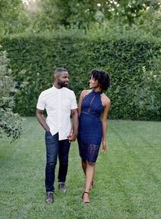 a man and woman standing in the grass holding hands