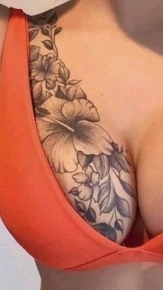 the back of a woman's breast with flowers on it and an orange tank top