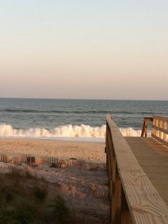 there is a bench on the beach next to the ocean with waves in the background