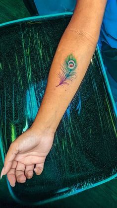 a woman's arm with a tattoo on it and a peacock feather in the middle