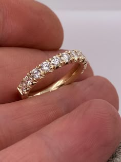 a hand holding a yellow gold ring with three diamonds on it's sides and the band