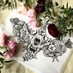 some flowers are sitting on a table next to a piece of paper with an image of a skull and roses