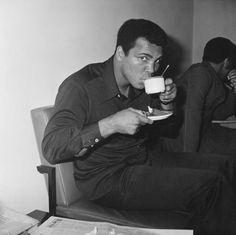 a man sitting in a chair drinking from a cup