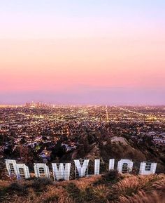 the hollywood sign is on top of a hill at dusk with city lights in the background