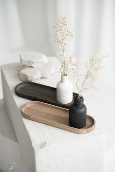 two vases with flowers in them sit on a tray next to towels and other items