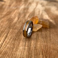 two rings with wood inlays are sitting on a table next to some rocks