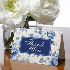 a blue and white thank you card sitting on top of a table next to flowers