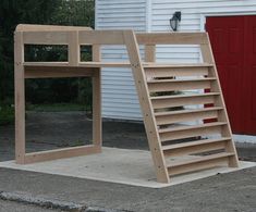 a wooden ladder sitting on top of a sidewalk next to a white building with a red door