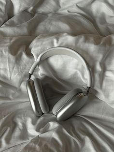 two headphones laying on top of a white sheet covered bed with the covers pulled down