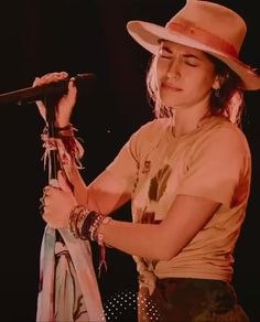 a woman wearing a hat and holding a microphone