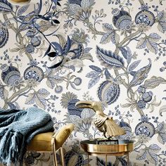 a blue and white floral wallpaper with an ornate design on the wall next to two chairs