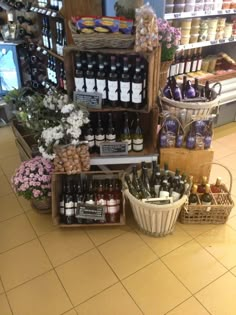 a store filled with lots of bottles of wine next to baskets full of food and flowers