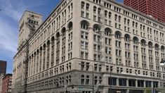 an old building in the middle of a city with tall buildings on both sides and cars driving down the street