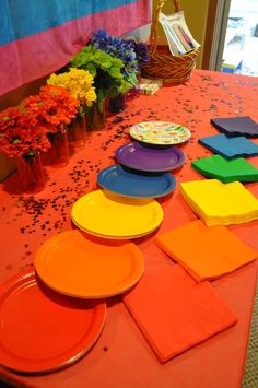 plates and napkins are laid out on an orange table cloth with flowers in the background