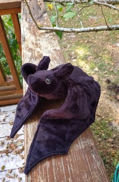 a purple stuffed animal laying on top of a wooden bench next to a tree branch