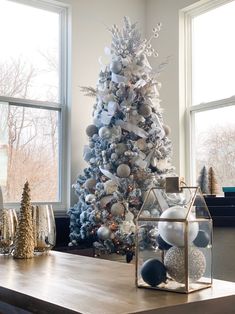 a decorated christmas tree in a living room next to a window with snowflakes on it