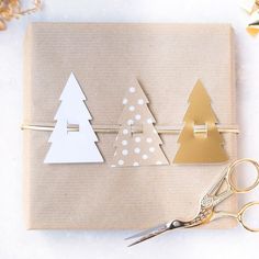 a pair of scissors sitting on top of a piece of paper next to some christmas trees