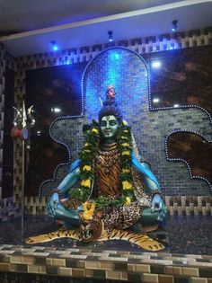 there is a buddha statue sitting in the middle of a tiled room with blue lights