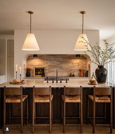 a kitchen island with stools and lights hanging from it's ceiling over the counter