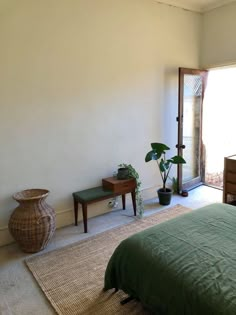 a bed room with a neatly made bed and two planters on the floor next to it