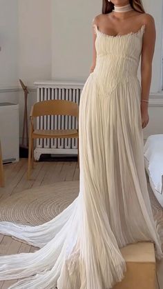 a woman in a white dress is standing on a wooden floor and posing for the camera