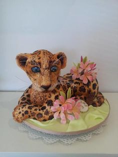 a leopard figurine sitting on top of a plate with flowers in front of it