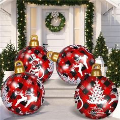 three red christmas baubles sitting in front of a white house decorated for the holidays