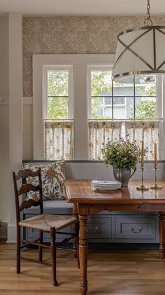 a dining room table with two chairs and a bench in front of the window,