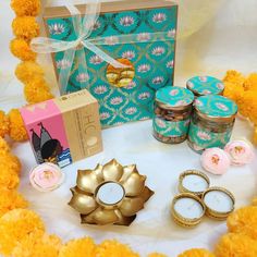 some candles and other items are on a table with flowers in the middle, along with a gift box