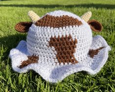 a crocheted cow hat sitting in the grass