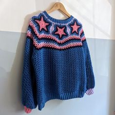 a blue sweater with pink stars is hanging on a wall