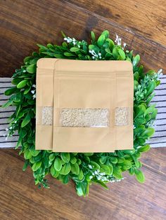 a brown paper bag sitting on top of a wooden table next to green leaves and flowers