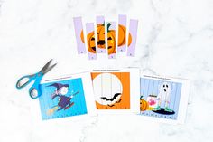 four halloween cards and scissors on a marble surface with the cut outs out to make them look like pumpkins