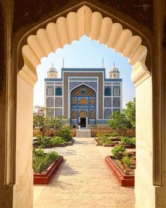 an archway leading to a blue and white building with many plants in the foreground