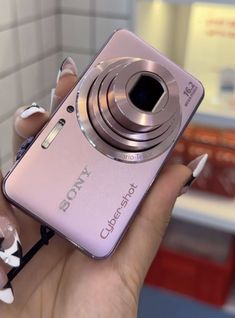 a woman holding a pink camera in her hand with white flowers on the front and bottom