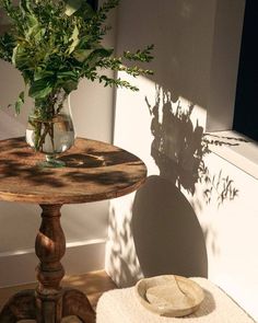 a small table with a vase on it next to a window sill and towel