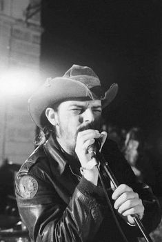 a man with a cowboy hat on singing into a microphone in front of an audience