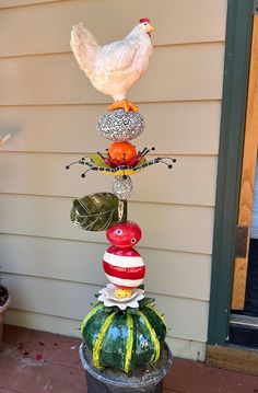 a white chicken sitting on top of a potted plant in front of a house