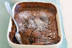 two white dishes filled with brownies and powdered sugar next to each other on a blue table cloth