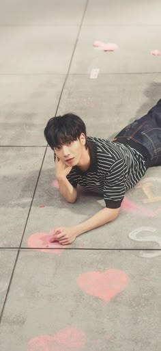 a young man laying on the ground next to chalk drawings