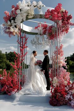 a bride and groom standing under an arch with flowers