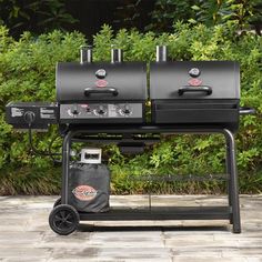 two bbq grills sitting next to each other on top of a stone patio