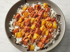 a bowl filled with rice and meat on top of a white countertop next to a fork