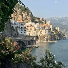 an old bridge crossing over the water in front of a city on top of a mountain